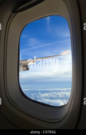 Vertikale Ansicht durch ein Flugzeug Fenster von Cumulus und Stratocumulus Wolken und Kondensstreifen über den Himmel. Stockfoto