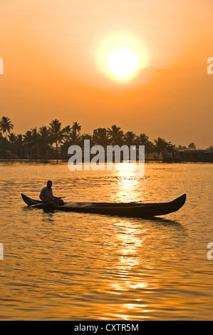 Vertikale Blick auf einen herrlichen Sonnenuntergang in den Backwaters von Kerala mit einem Fischer paddelt sein Kanu im Vordergrund. Stockfoto