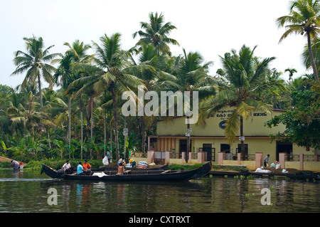 Horizontale Ansicht einer kleinen Fabrik mit Arbeitern in Booten hochziehen zum Be- und Entladen von Fracht entlang des Flussufers in Kerala. Stockfoto