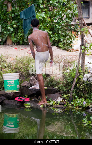 Vertikale Porträt eines Mannes, waschen sich selbst von der Seite des Flusses in Kerala. Stockfoto