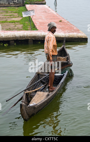 Vertikale Ansicht von einem traditionellen Fischer in seinem Fischerboot heraus auf den Backwaters von Kerala, Angeln für Muscheln. Stockfoto