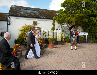 Eine Piper at Gretna führt das Brautpaar mit dem fotogenen Bogen für Bilder zu treffenden.  SCO 8653 Stockfoto