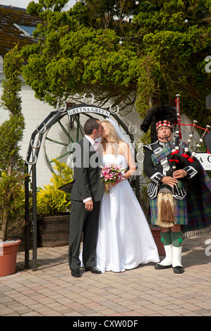Eine Piper at Gretna führt das Brautpaar mit dem fotogenen Bogen für Bilder zu treffenden.  SCO 8654 Stockfoto