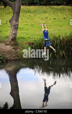 Ein Junge spielt auf einem Seil schwingen, über den Fluß Teme in der Nähe des Dorfes Leintwardine, Herefordshire UK