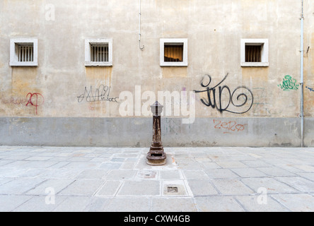 Eine gusseiserne öffentliche Trinkbrunnen auf einem Platz in Venedig vor einer Wand mit Graffiti und kleinen quadratischen Fenster Stockfoto