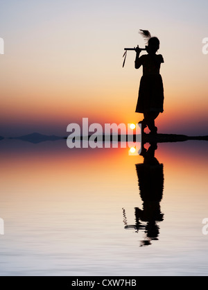 Silhouette eines indischen Mädchen vorgibt, Lord Krishna bei Sonnenuntergang mit Wasserreflexion und Wellen zu sein. Indien Stockfoto