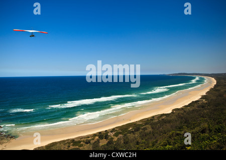 Rote und weiße Drachen fliegen hoch über Strand von Byron Bay in New South Wales Stockfoto