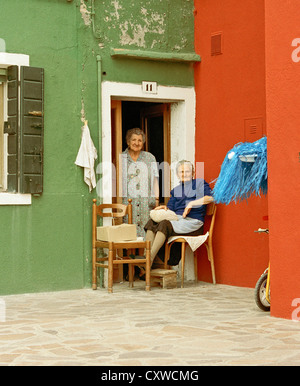 ältere Damen in der Tür eines Hauses auf der Insel Burano, Venedig, Italien. die Insel ist bekannt für seine Spitze arbeiten. Stockfoto