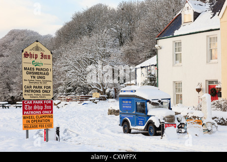 Schilder und Oldtimer werben für die Ship Inn Historic Village Pub im Winterschnee in Red Wharf Bay, Insel Anglesey, Nordwales, Großbritannien Stockfoto