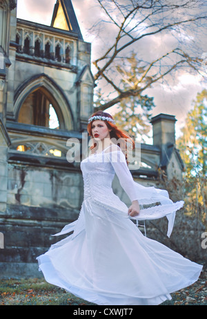 Zwirbelte Mädchen mit roten Haaren vor einer großen Burg trägt ein atemberaubende weiße Hochzeitskleid Stockfoto