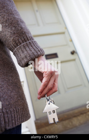 Frau, die Schlüssel zu neuen Zuhause vor der Tür Stockfoto