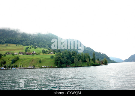 Häuser am Hang eines Berges neben dem Vierwaldstättersee. In ein schöner Anblick rollt sich Nebel über der Oberseite des Berges. Stockfoto