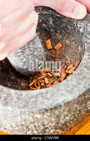 Frischen Zimt wird in einem Marmor Mörser gemahlen Stockfoto