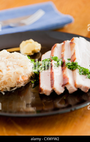 Traditionelle deutsche Küche, gebratenes Schweinefleisch mit Sauerkraut. Mit Senf und Petersilie serviert Stockfoto