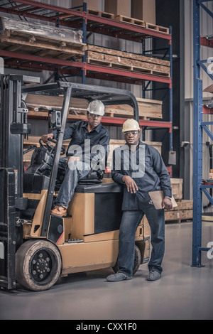 Afrikanische amerikanische Arbeiter mit Gabelstapler in Fabrik Stockfoto