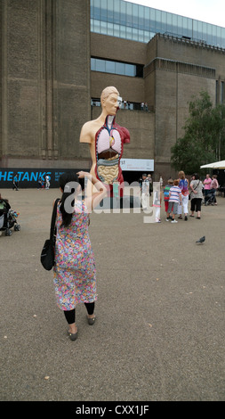 Person mit Blick auf Damien Hirst Kunstwerk 'Lied' mit einem Mobiltelefon außerhalb der Tate Modern Gallery Sommer London England 2012 UK KATHY DEWITT DE WITT Stockfoto