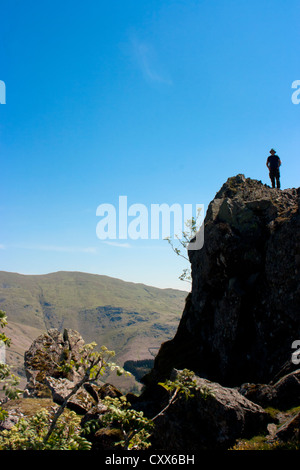 Fiel Wanderer auf dem "Löwen" Felsen am Gipfel des Helm Crag den Felsen, bekannt als der Löwe und das Lamm Grasmere, Lake District Stockfoto