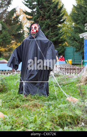 Vogelscheuche im schwarzen Mantel steht mitten im Garten. Halloween-Dekorationen. Russland Stockfoto