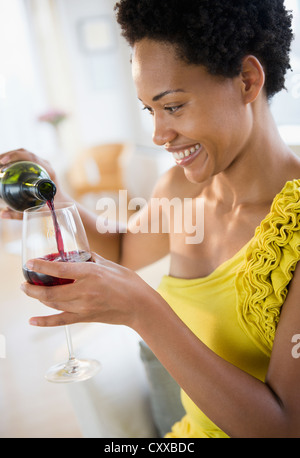 Afroamerikanische Frau Gießen Rotwein Stockfoto