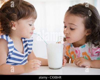 Gemischte Rassen Schwestern teilen Glas Milch Stockfoto