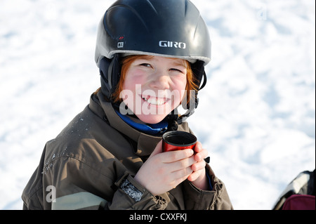 Junge, trinken eine Tasse Tee, während der Wintersport im Schnee Stockfoto