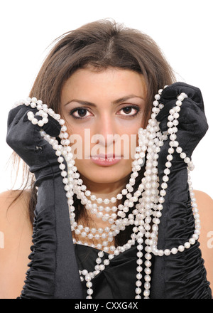 Junge Frau in einem schwarzen Kleid, schwarze Handschuhe und eine lange Perlenkette Stockfoto