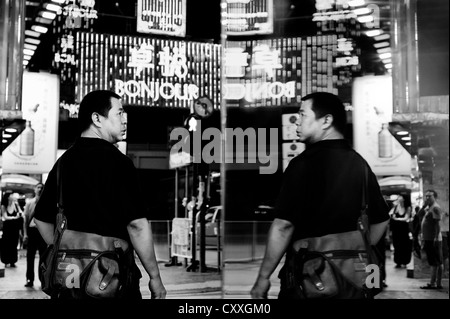 Kowloon, Hong Kong. Straßenszene in der Nacht mit Reflexion in einem Schaufenster. Stockfoto