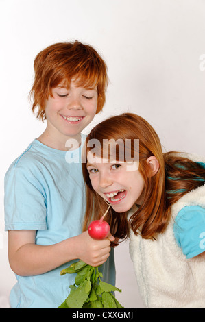 Mädchen und jungen Boy Fütterung einen Rettich mit einer Mädchen Stockfoto