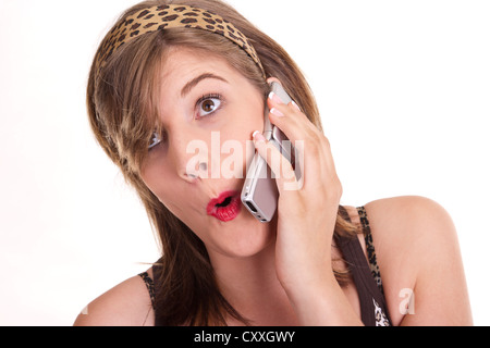 Überrascht, junge Frau, die ein Handy an ihr Ohr halten Stockfoto