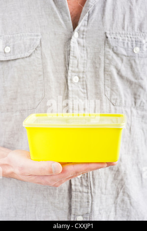 Vorderseite des Mannes mit einer gelben Kunststoff-Box in der hand Stockfoto