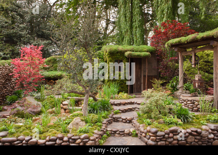 Ein kleiner japanischer Zen-Garten mit moosbedeckten Steinen Stein und Wasser verfügen über einen kleinen Teich - Acer palmatum Bäume Steingarten Pfad Pfade UK Stockfoto