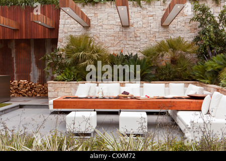 Urbaner moderner, zeitgenössischer Garten mit Gartenmöbeln im Freien, Sofa, Sitzbereich, gepflasterter gepflasterter Innenhof, Chelsea Flower Show Gardens, Großbritannien Stockfoto