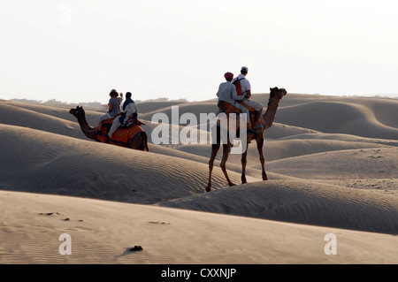 Touristen, Kamelreiten Dromedar, arabischen Kamele (Camelus Dromedarius), mit Führungen in der Wüste Thar-Wüste, Rajasthan, Indien Stockfoto