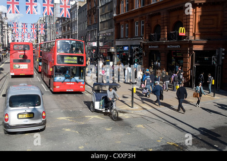 Verkehr auf der Oxford Street, Doppeldecker-Busse, Fahrrad Taxi, Union Jack, Nationalflagge, London, England, Vereinigtes Königreich, Europa Stockfoto