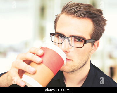 Junger Geschäftsmann mit Brille, hält eine Tasse Kaffee, eine Pause Stockfoto