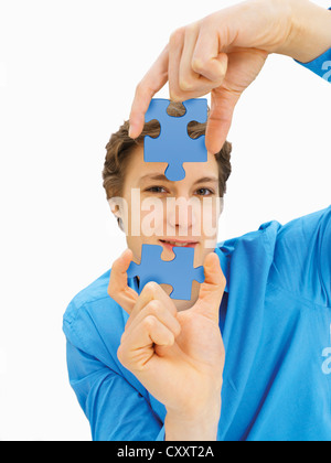 Junger Mann hält Teile eines Puzzles Stockfoto