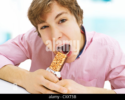 Junger Mann einen Müsliriegel Essen Stockfoto