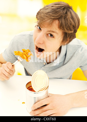 Kann der junge Mann isst Ravioli aus der Dose Stockfoto