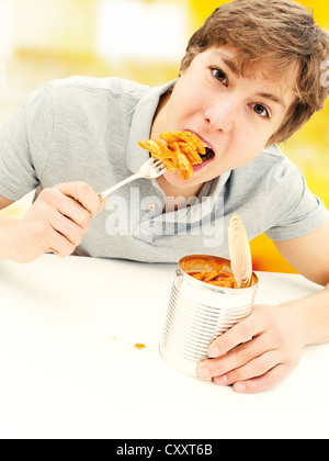 Kann der junge Mann isst Ravioli aus der Dose Stockfoto