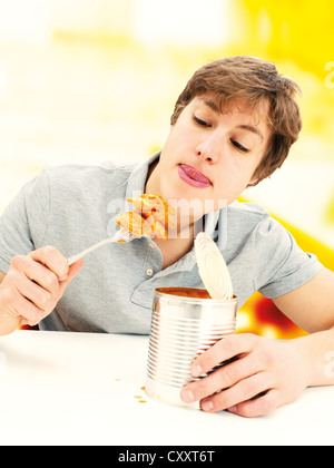 Kann der junge Mann isst Ravioli aus der Dose Stockfoto