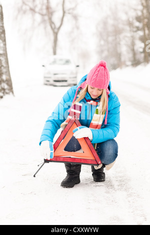 Frau weglegen Dreieck Auto Aufschlüsselung Winter Schnee Warnschild Stockfoto