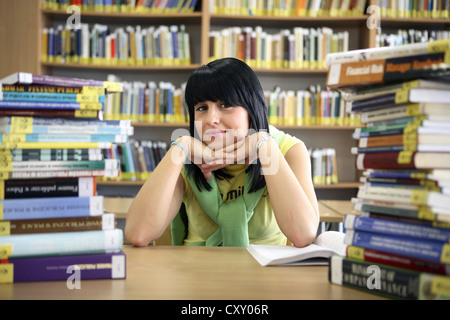 Student mit Stapeln von Büchern in einer Universitätsbibliothek Stockfoto