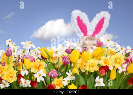 Frau mit Hasenohren, versteckt in einer Blumenwiese Stockfoto