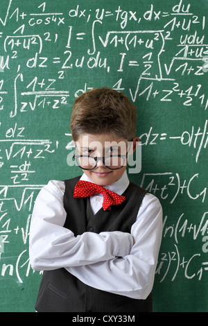 Schuljunge Brillen-und eine Fliege vor einer Tafel mit mathematischen Gleichungen Stockfoto