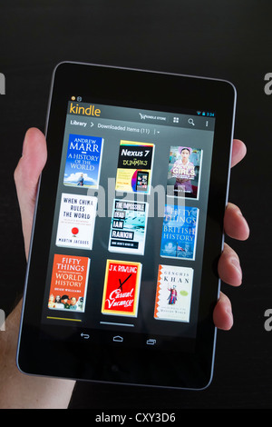 Mann, hält Google Nexus 7 Tablet PC android Betriebssystem ausführen und e-Bücher in der Bibliothek durchsuchen