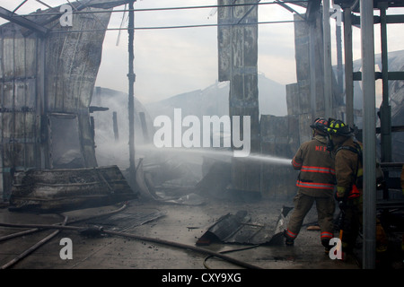 Lannon Feuerwehr Aufsprühen von Wasser auf einem eingestürzten Gebäudes Feuer Stockfoto