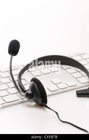Büro-Kopfhörer mit Mikrofon über weiße Tastatur am Schreibtisch Stockfoto
