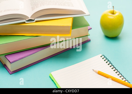 Bleistift auf Notizblock mit Schulbüchern und Apfel auf Schüler-Schreibtisch Stockfoto