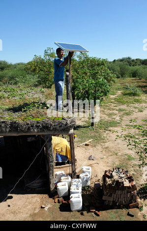 Junger Mann Berg Solarzellen auf dem Dach eine einfache Hütte ein wirtschaftender Bauernhof, Gran Chaco, Provinz Santiago Del Estero Stockfoto