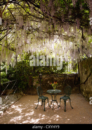 Runden, gusseisernen Garten Bistro-Tisch mit zwei Stühlen in einem romantischen Hinterhof Stockfoto